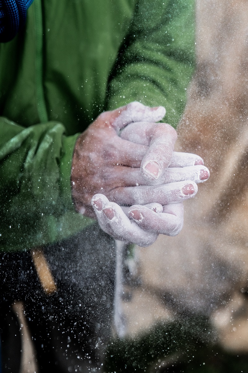 A climber putting chalk on their hands to improve grip and reduce sweat.