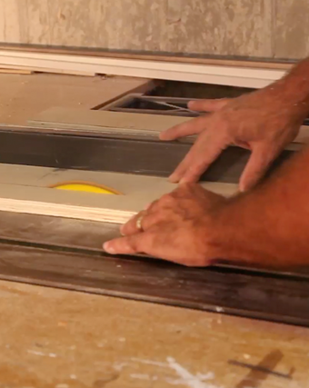 Woodworker working on cutting a piece of wood in a small home-based woodshop.